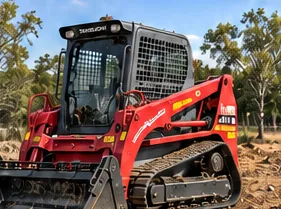 Red tracked skid steer with bucket on a cleared site